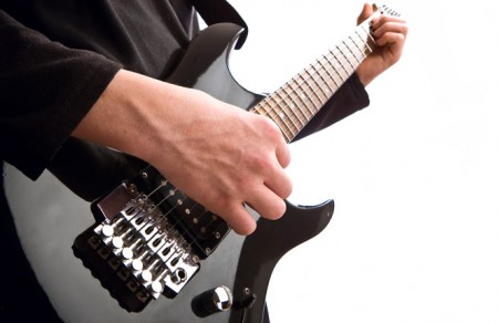 A close up of a man playing an electric guitar